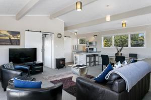een woonkamer met een bank en stoelen en een televisie bij Lakeview's On Richmond in Taupo