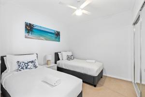 a bedroom with two beds and a ceiling fan at Harbour Quays Apartments in Gold Coast