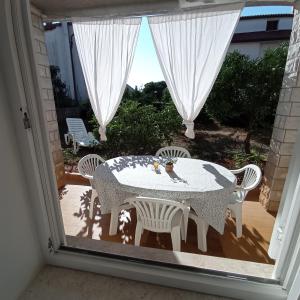 a table and chairs on a patio with a window at Apartment MONAS I in Pješčana Uvala 