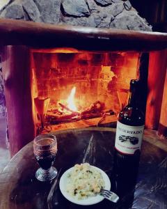 a bottle of wine and a plate of food next to a fireplace at Pousada e Hostel Caminho de Santiago in Alto Paraíso de Goiás