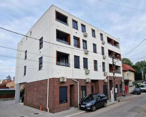 un bâtiment blanc avec une voiture garée devant dans l'établissement Sunflower apartment, à Niš