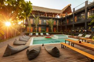 a resort with a swimming pool and benches and a building at Che Puerto Escondido Hostel & Bar Adults Only in Puerto Escondido