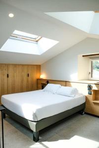 a bedroom with a large white bed with a skylight at Logis Hotel Erreguina in Banca