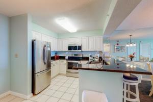 a kitchen with white cabinets and a stainless steel refrigerator at Pelican Beach Resort 1717 in Destin