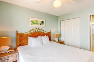 sypialnia z białym łóżkiem z drewnianym zagłówkiem w obiekcie Pelican Beach Resort 1717 w mieście Destin