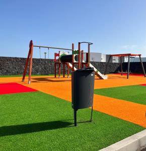 a playground with a trash can on the grass at Casa el Timple in Costa Teguise