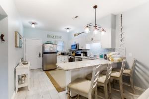 une cuisine avec des placards blancs et un îlot de cuisine avec des chaises dans l'établissement Baywatch F4, à Pensacola Beach