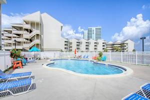 a swimming pool with chairs and a building at Baywatch F2 in Pensacola Beach