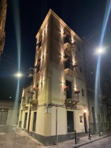 ein großes weißes Gebäude mit zwei Balkonen und Lichtern in der Unterkunft VICOLO SAN GAETANO -luxury rooms- in Catania
