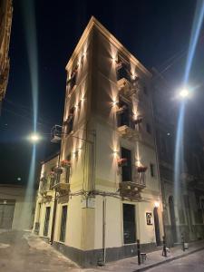 a large white building with two balconies and lights at VICOLO SAN GAETANO -luxury rooms- in Catania
