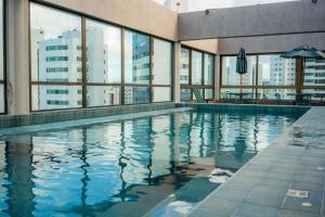 a swimming pool with a view of a building at Rooftop 470 - Novíssimo Flat Boa Viagem in Recife
