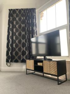 uma sala de estar com uma televisão de ecrã plano e uma janela em Stylish 91sqm Victoria 2 bedroom Apartment em Bristol