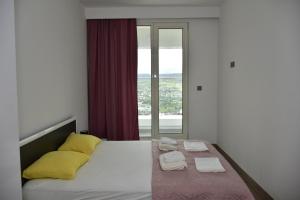 ein Schlafzimmer mit einem Bett mit gelben Kissen und einem Fenster in der Unterkunft High Apartment in Skopje