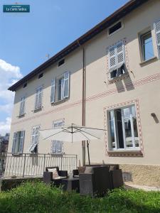 a building with an umbrella and chairs in front of it at B&B La Corte Antica - Luino Lago Maggiore in Luino