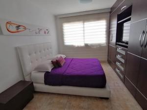 a bedroom with a purple bed and a tv at Lo mejor de isla Margarita in Pampatar