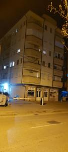 un gran edificio con un estacionamiento por la noche en D-apartmani, en Bijeljina