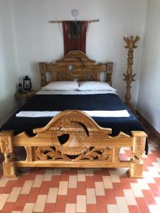 - un grand lit en bois dans une chambre avec un sol en damier dans l'établissement Villa Alejandra, à Guatapé