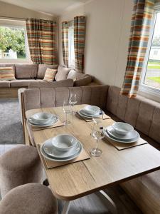 a dining room table with plates and wine glasses at Cosy Caravan in Ulrome