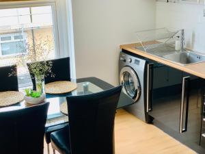 uma cozinha com uma mesa e uma máquina de lavar roupa em Stylish 91sqm Victoria 2 bedroom Apartment em Bristol