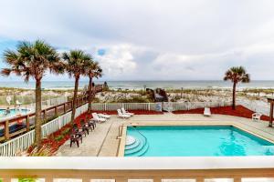 a swimming pool with palm trees and the beach at Veranda 101 in Fort Walton Beach
