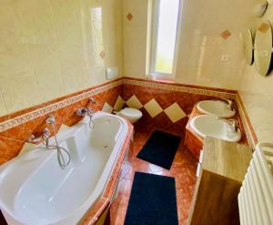 a bathroom with two sinks and a tub and two toilets at Dharma Horse Shelter Bungalows & Farmping in Siófok