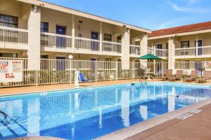 a swimming pool in front of a building with a hotel at Motel 6-Baytown, TX - Garth Rd in Baytown