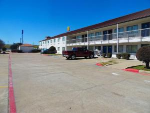 un camión rojo estacionado frente a un edificio en Motel 6-Ennis, TX, en Ennis