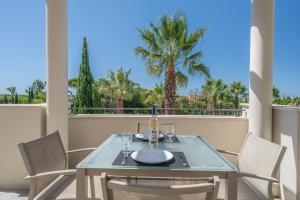 einen Tisch und Stühle auf einem Balkon mit Palmen in der Unterkunft Fabulous 2 bedroom apartment Pine Hills in Vilamoura