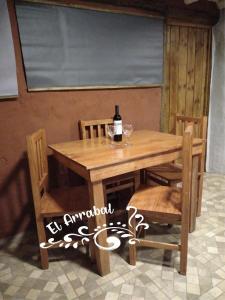 a wooden table and chairs with a bottle of wine on it at EL ARRABAL in Uspallata