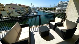 two chairs and a table on a balcony with a harbor at Apartamento con vistas a mar y canal. Empuriabrava in Empuriabrava