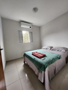 a bedroom with a bed with a green blanket on it at DOURADOS GUEST FLAT PEDRA BONITA in Dourados