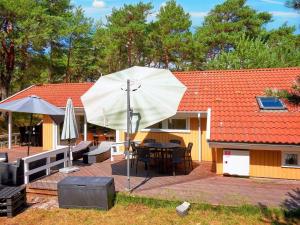 un patio con una mesa y una sombrilla blanca en Holiday home Nexø X en Vester Sømarken