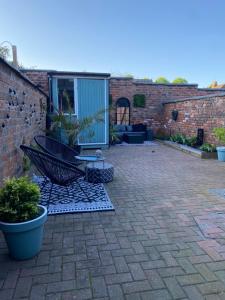 a patio with a chair and a table on a brick wall at Luxury Spacious Renovated Townhouse in Grantham