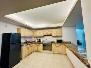 a kitchen with wooden cabinets and a black refrigerator at BRISAS GUITARRON in Acapulco