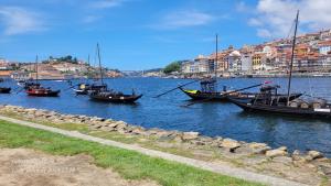 eine Gruppe von Booten, die in einem Fluss mit Gebäuden sitzen in der Unterkunft Casa da Praia in Vila Nova de Gaia