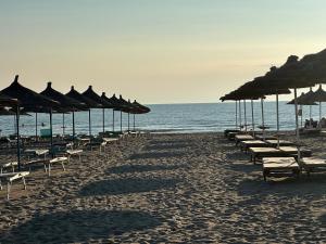 a row of chairs and umbrellas on a beach at Luxury Apartment - San Pietro in Durrës