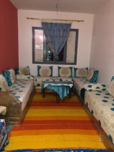 ein Wohnzimmer mit 3 Betten und einem Tisch in der Unterkunft Heart appartement Al massira in Agadir