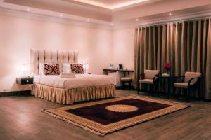 a bedroom with a bed and a table and chairs at Falettis Grand Bahawalpur in Bahawalpur