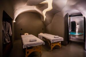 a massage room with two beds and a swimming pool at Kivotos Santorini in Imerovigli