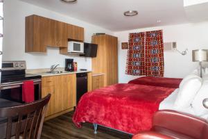 a hotel room with a red bed and a kitchen at Motel LA RÉFÉRENCE in Trois-Rivières