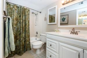 a bathroom with a toilet and a sink at Surf Dweller 207 in Fort Walton Beach +18 photos
