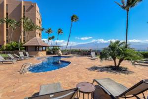 a resort with a pool and chairs and palm trees at Island Sands Resort 302 in Wailuku