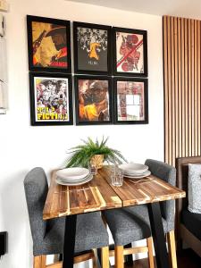 una mesa de comedor y sillas con cuadros en la pared en Le Cocon proche Paris JO 2024 Centre-ville, en Saint-Gratien