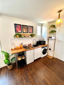 a kitchen with white cabinets and a wooden floor at Le Cocon proche Paris JO 2024 Centre-ville in Saint-Gratien