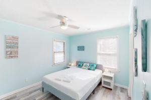 a blue bedroom with a bed and two windows at Offshore Oasis KDH101 in Kill Devil Hills