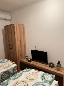 a room with two beds and a television on a desk at Guest Radic Apartment 3 in Palić