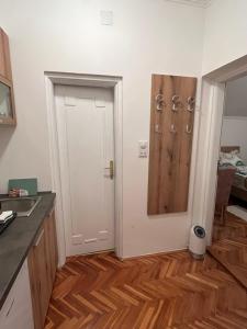 a kitchen with a white door and a wooden floor at Guest Radic Apartment 3 in Palić
