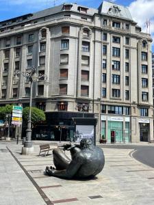 una estatua de una mujer tumbada en el suelo frente a un edificio en VISTAS A SANTO DOMINGO, en León