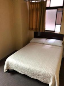 1 dormitorio con 1 cama blanca y ventana en Hotel Presidente, en Quito