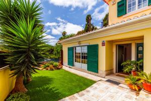 uma casa com persianas verdes e um quintal em Jacuzzi, garden, pool & barbecue beach House, 15mn from Lisbon center em Oeiras